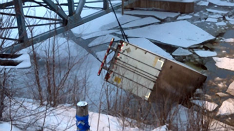 Work crews pull a semi trailer from icy Red Cedar River in Menomonie, WI after an 18 wheeler plunged into the river cab-first, killing the driver. Rescue crews were still searching for a passenger who was in the big rig at the time. Photo credit: WEAU-TV